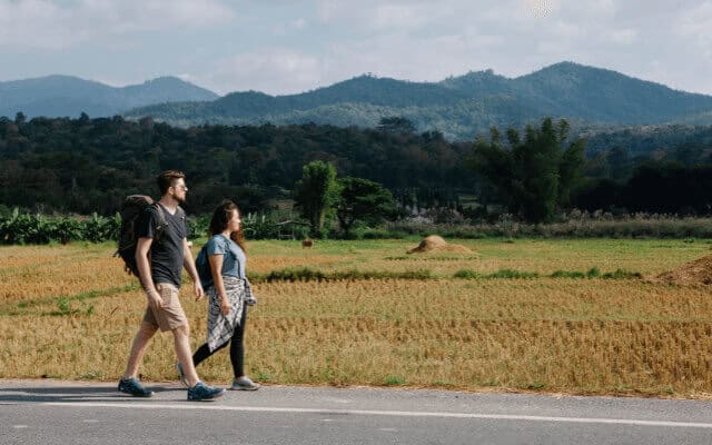 A couple walking along a road through a scenic countryside.