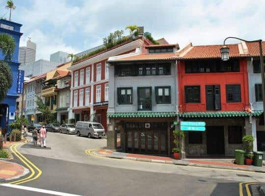 A vibrant street view of Ann Siang Hill in Singapore's Chinatown, lined with colorful heritage shophouses in shades of red, white, and blue. Credits to Elisa_Rolle.