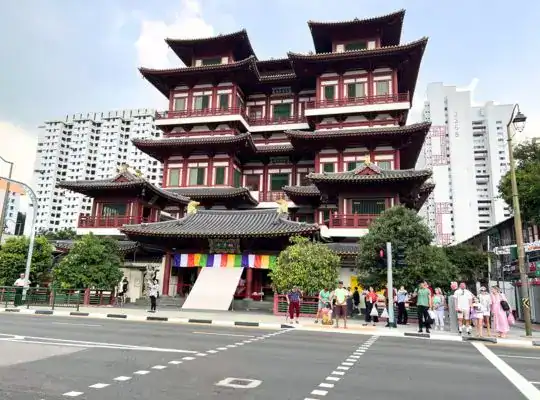 The Buddha Tooth Relic Temple in Singapore’s Chinatown, featuring traditional Chinese architecture and visitors crossing the street.